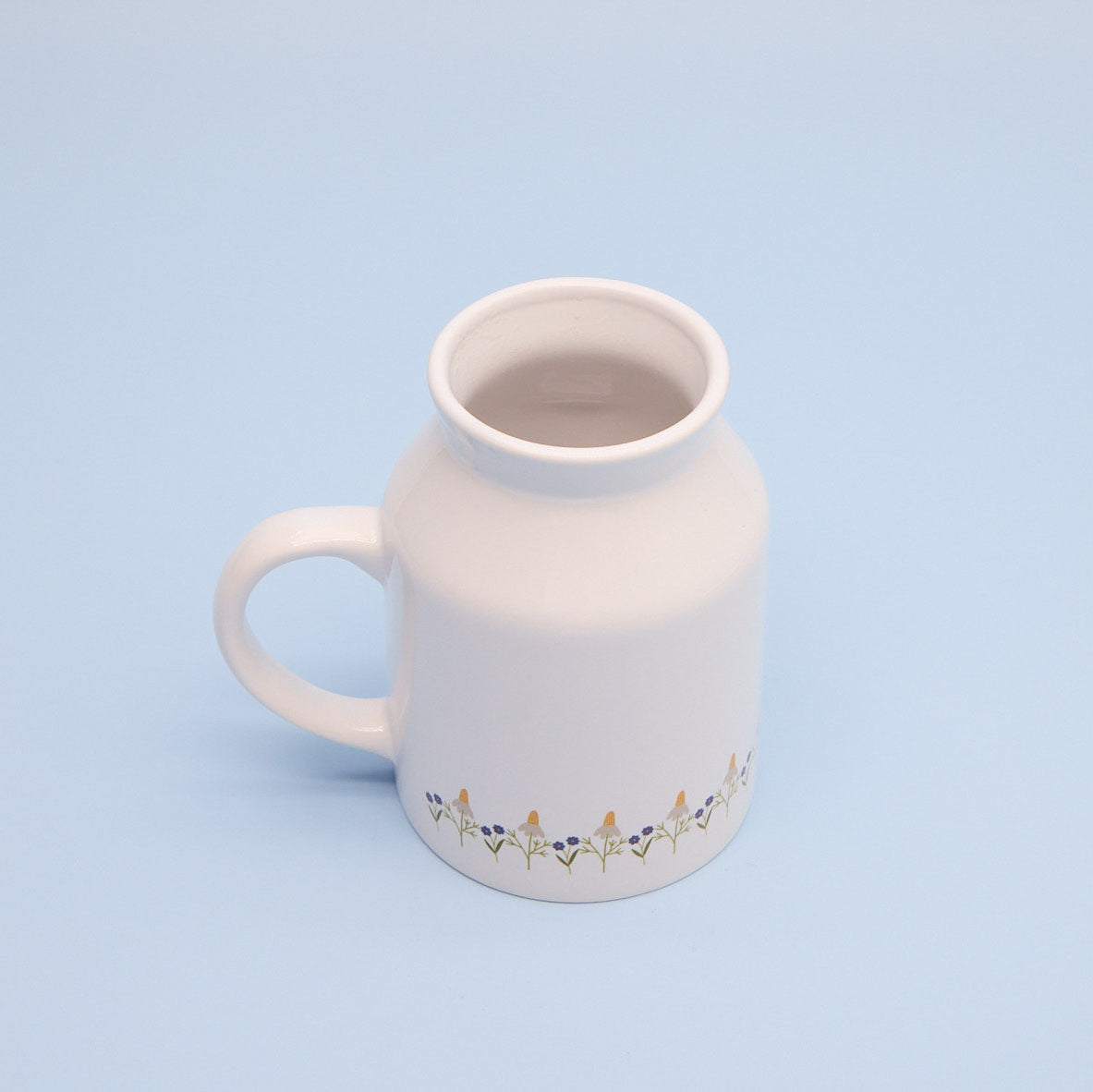 White sublimation milk jug with floral design on a light blue background