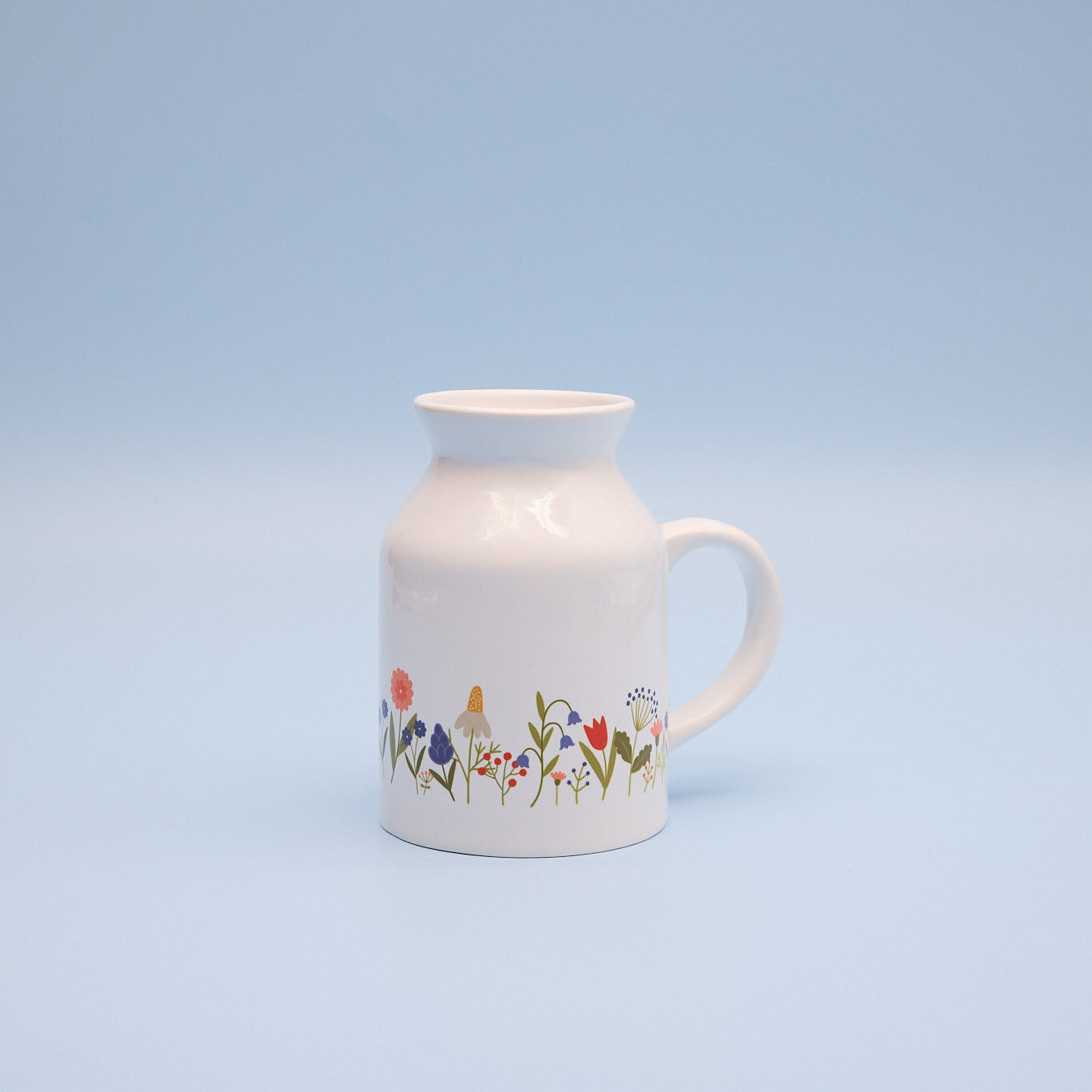 White milk jug with floral design on a light blue background