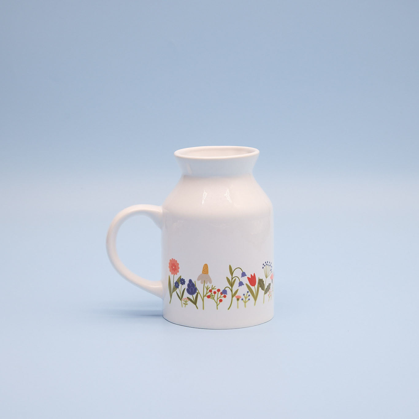 White milk jug with floral design on a light blue background