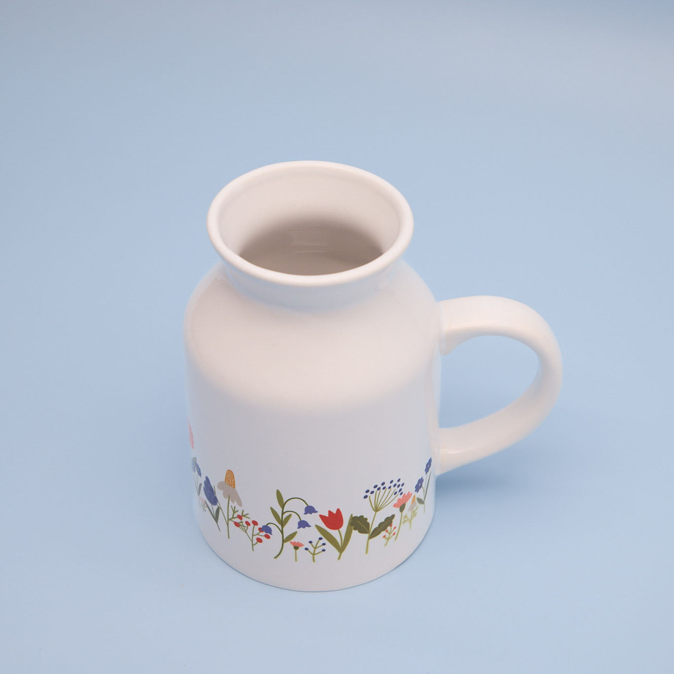 White sublimation milk jug with floral design on a light blue background